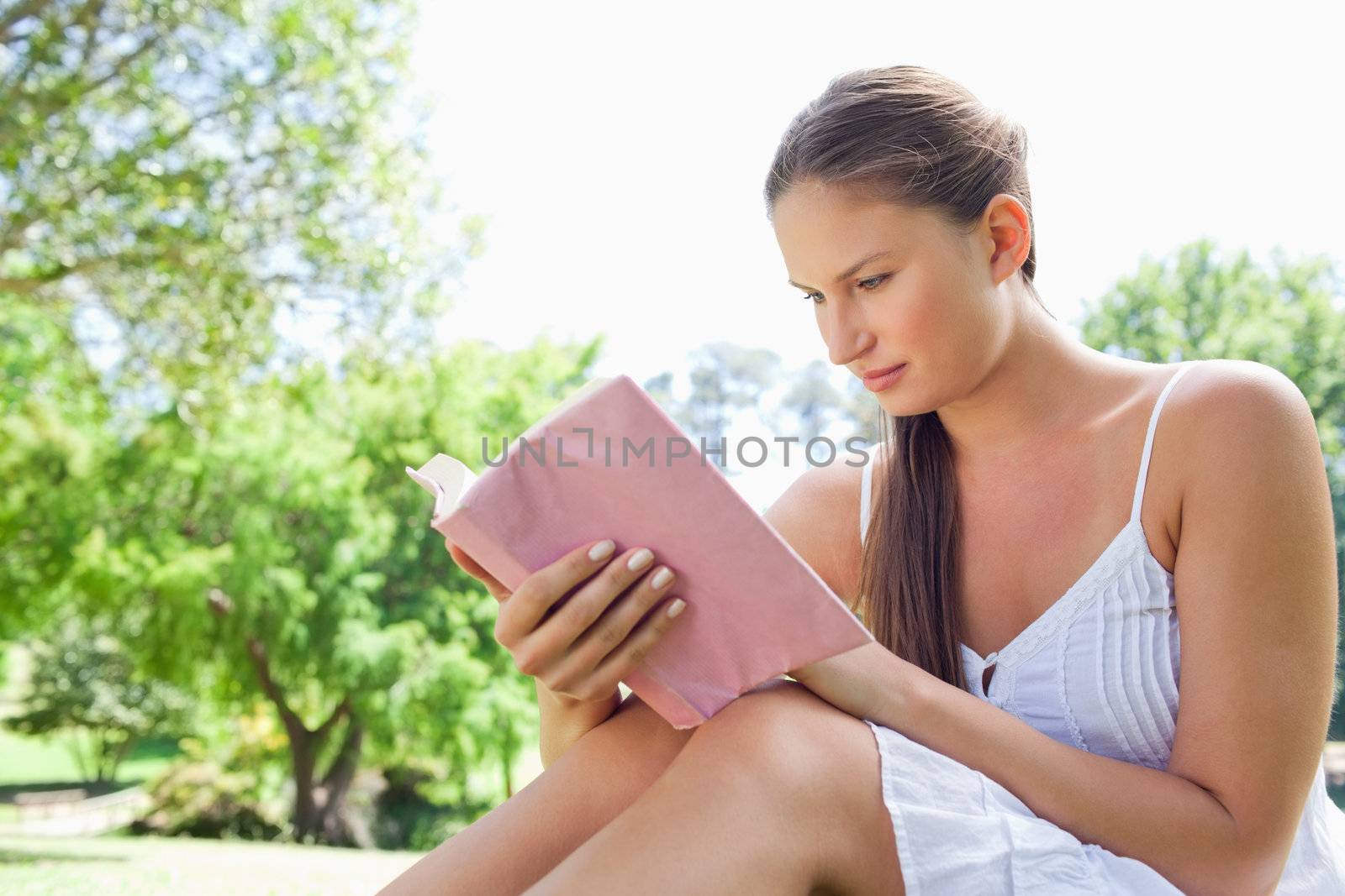 Side view of a woman reading a novel in the park by Wavebreakmedia