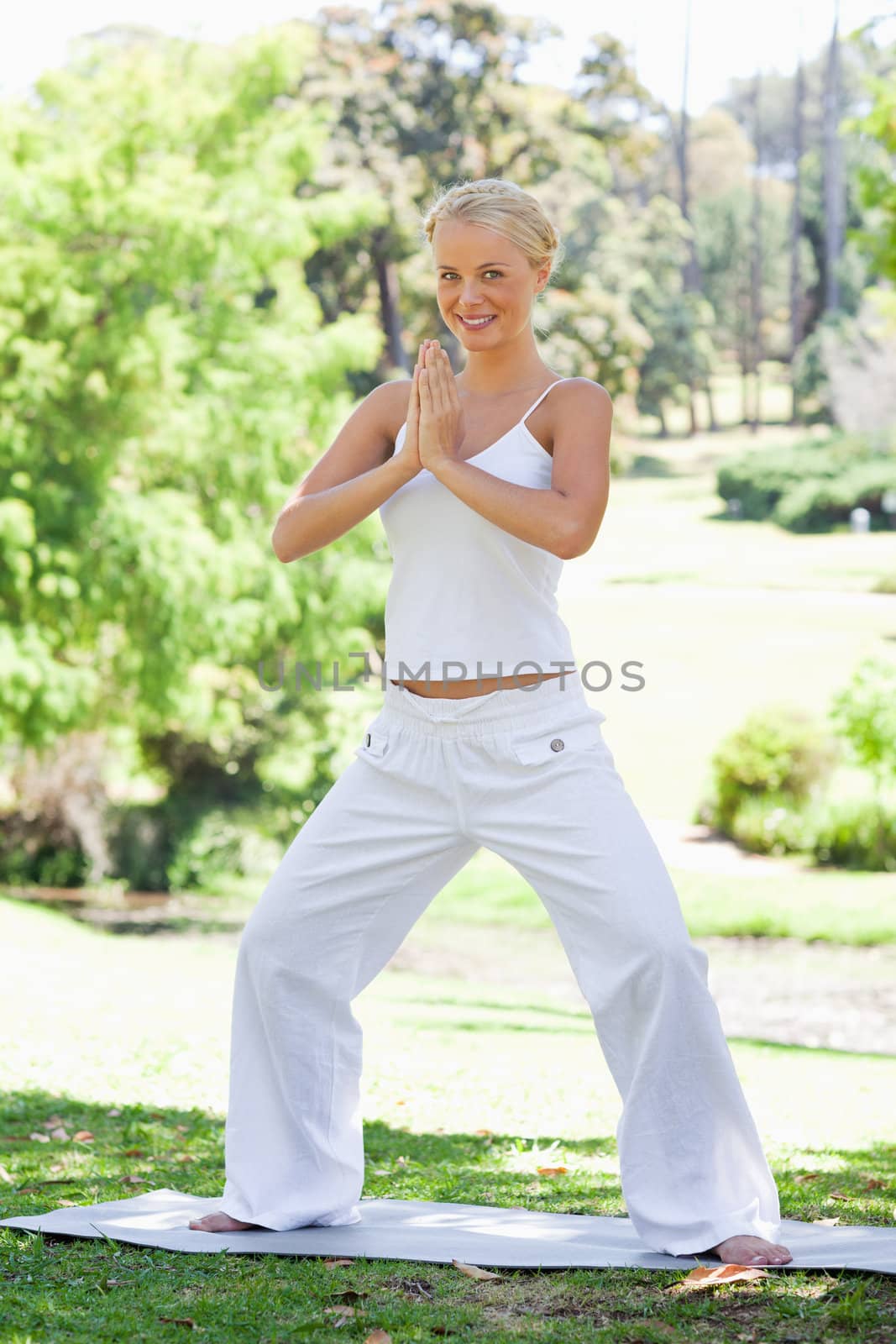 Smiling young woman doing yoga exercises in the park