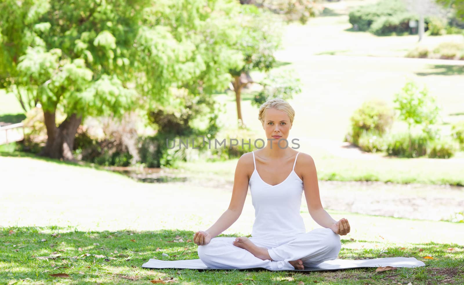 Woman sitting in a yoga position in the park by Wavebreakmedia