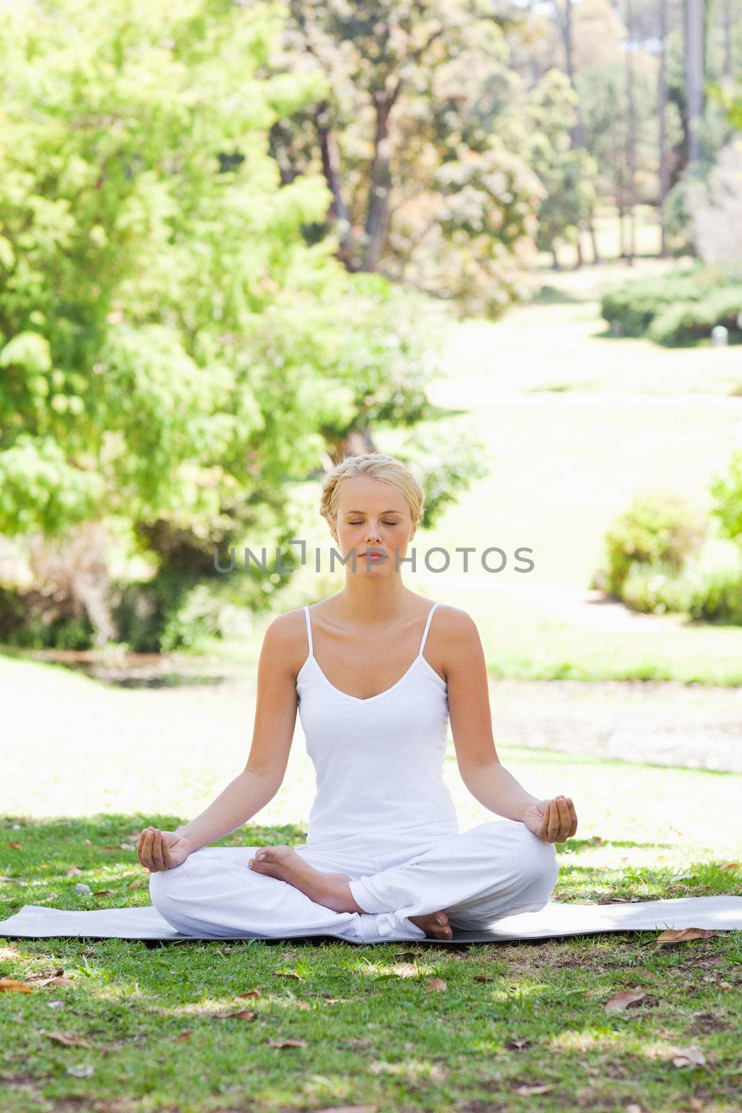 Woman sitting in a yoga position on the grass by Wavebreakmedia