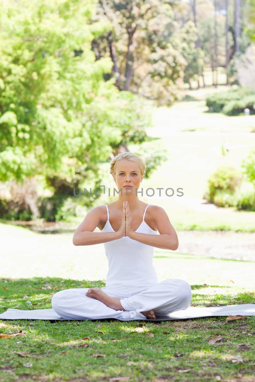 Young woman sitting in the park in a yoga position