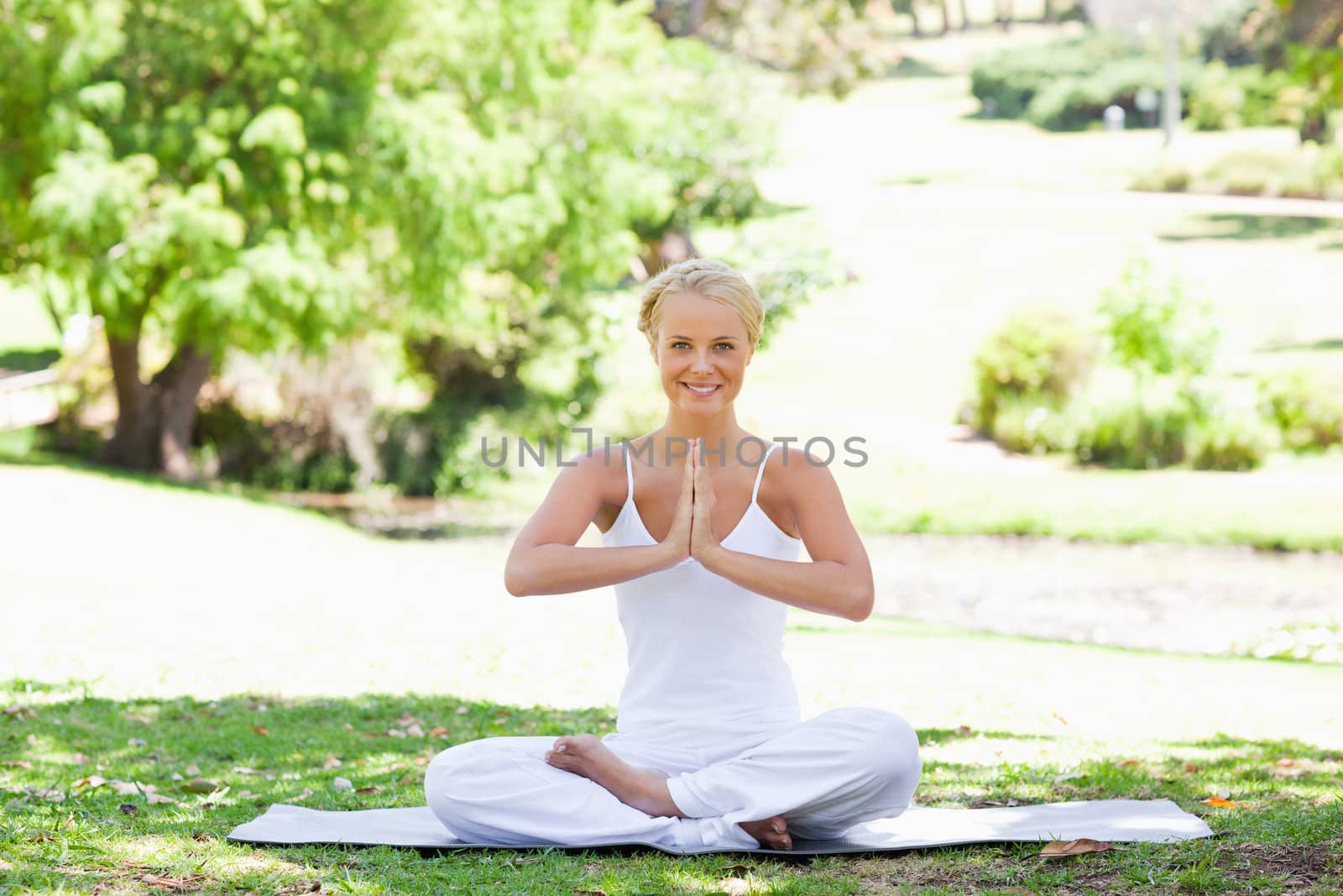 Smiling young woman sitting in a yoga position on the lawn