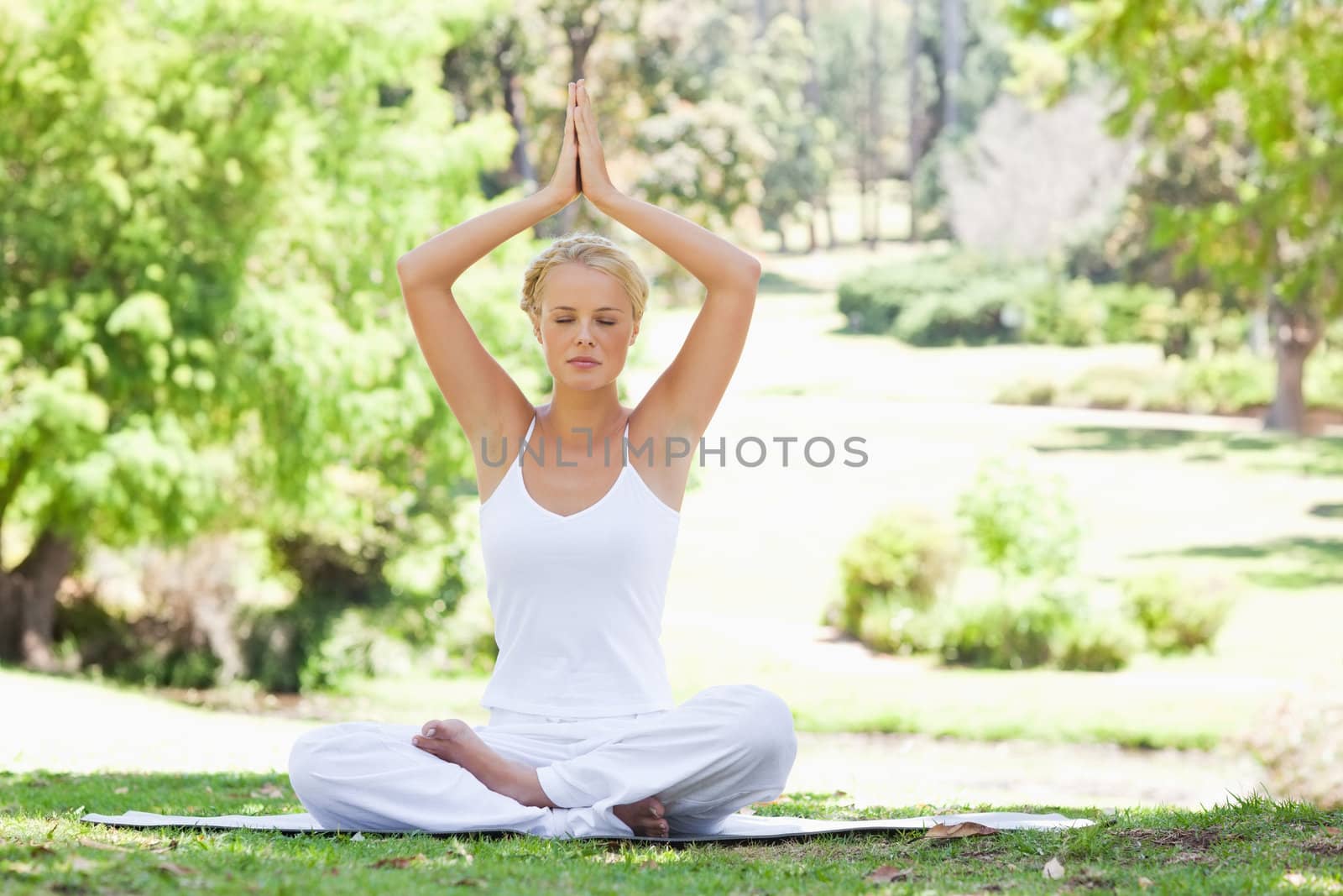 Woman sitting in a yoga position outdoors by Wavebreakmedia