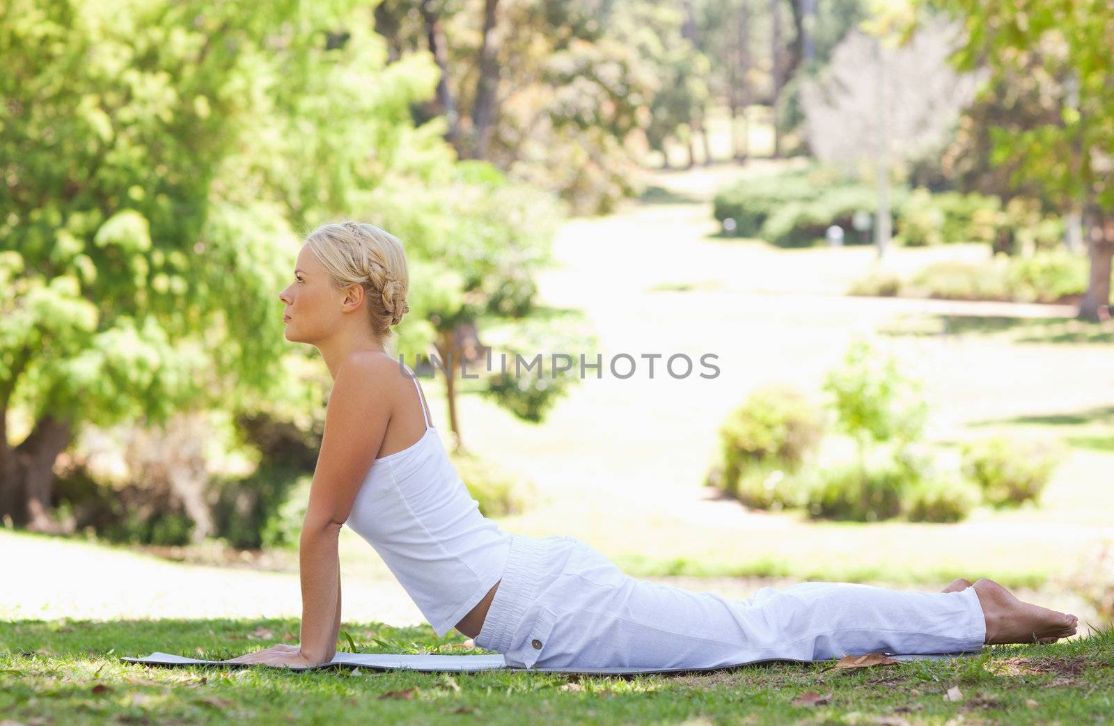 Side view of a young woman doing stretches on the grass