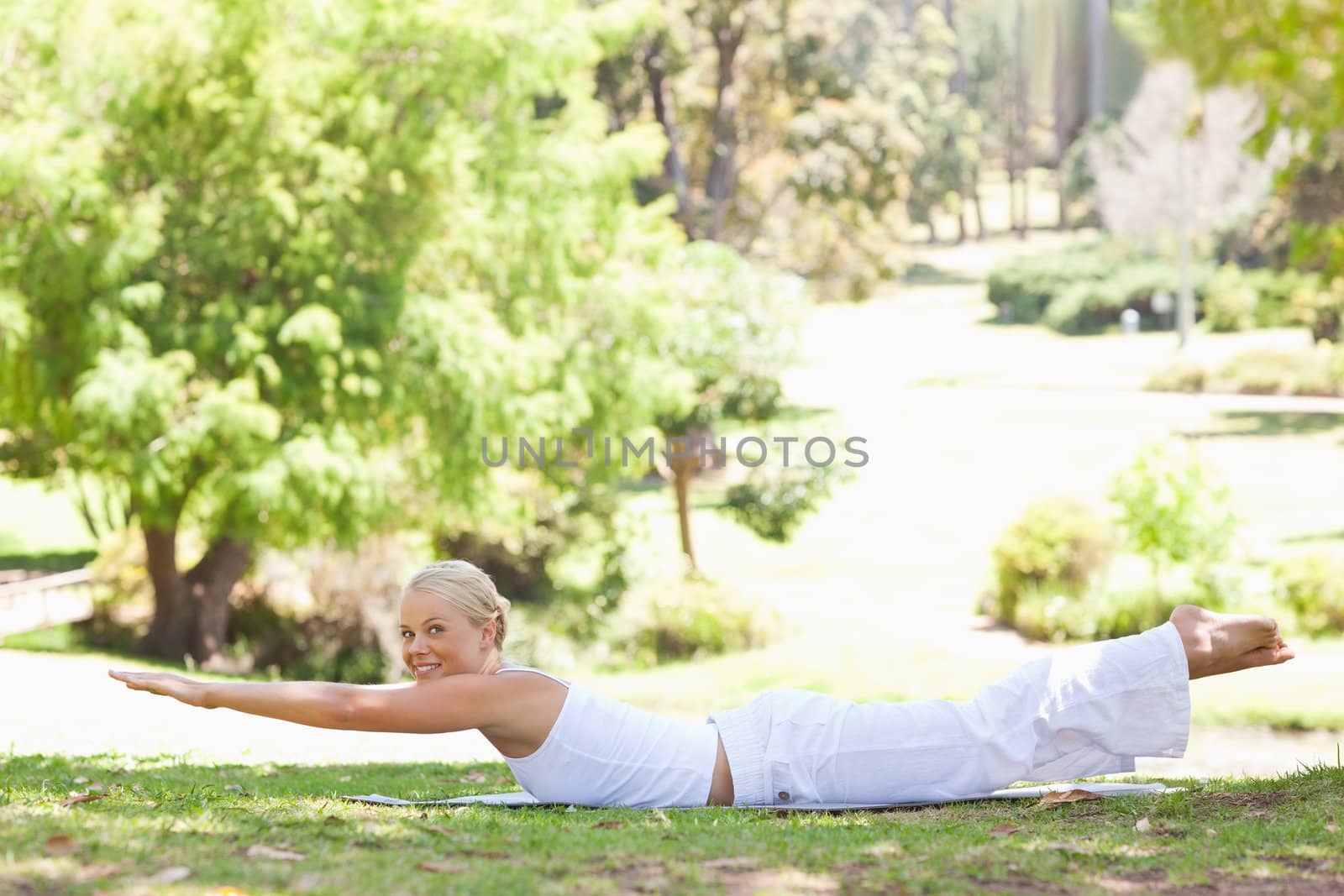 Side view of a smiling woman doing her exercises in the park by Wavebreakmedia