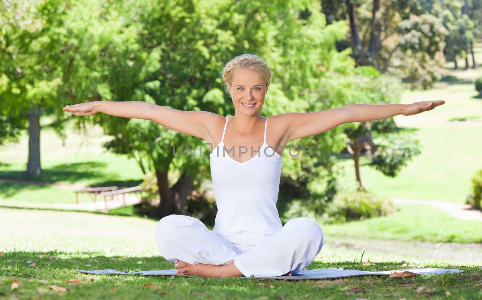 Smiling young woman on the lawn doing yoga exercises