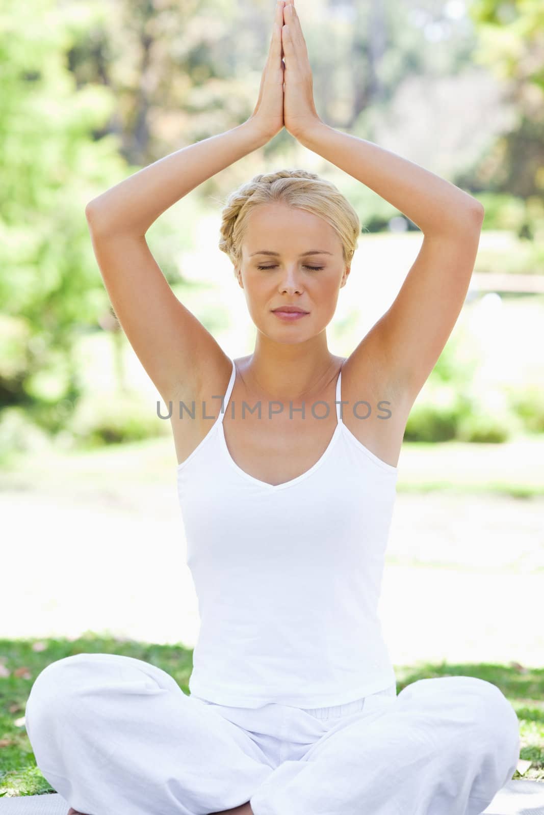 Relaxed woman in a yoga position on the meadow by Wavebreakmedia