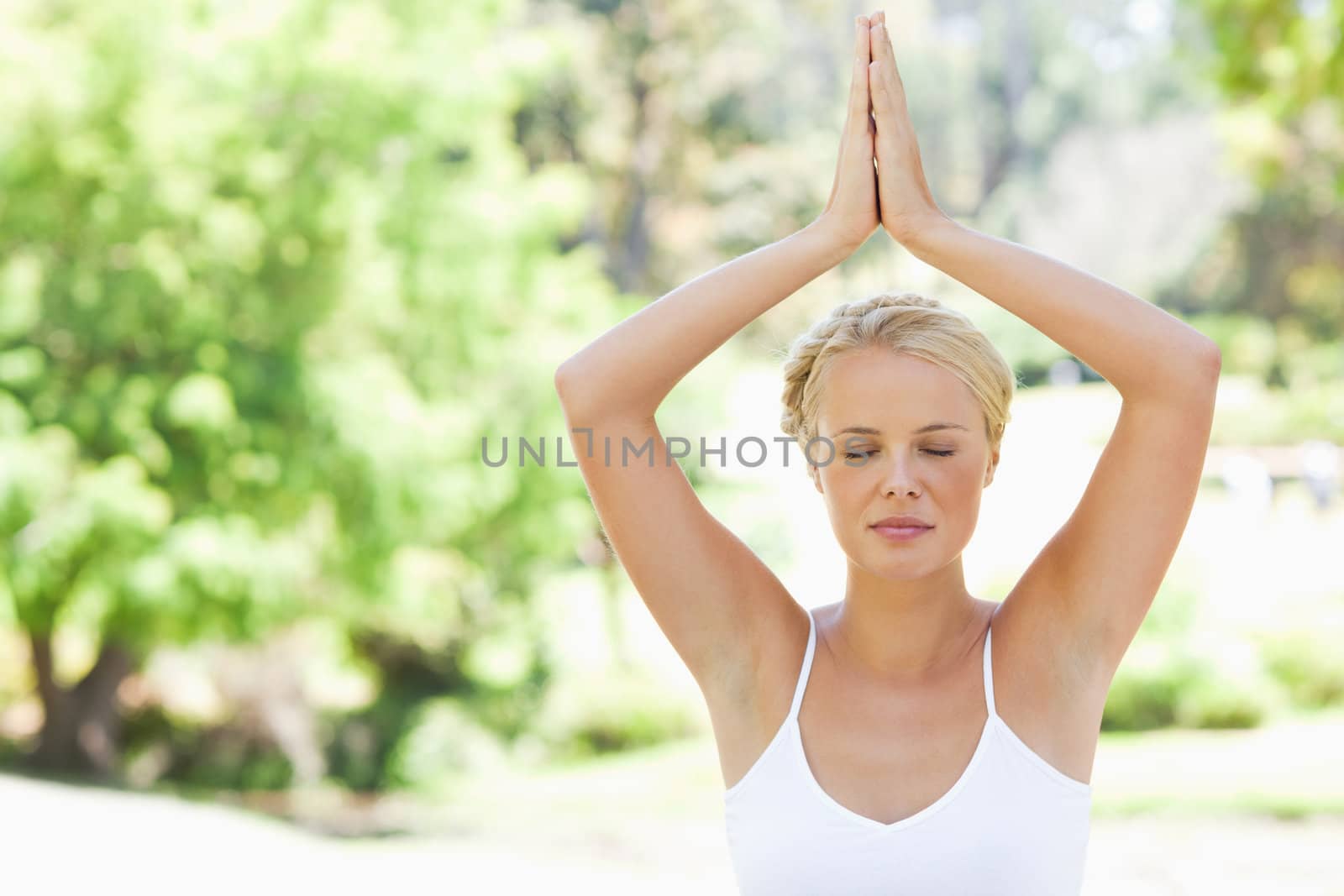 Relaxed woman in a yoga position in the park by Wavebreakmedia