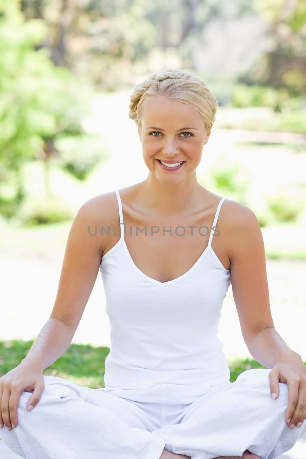 Smiling young woman in a yoga position on the lawn