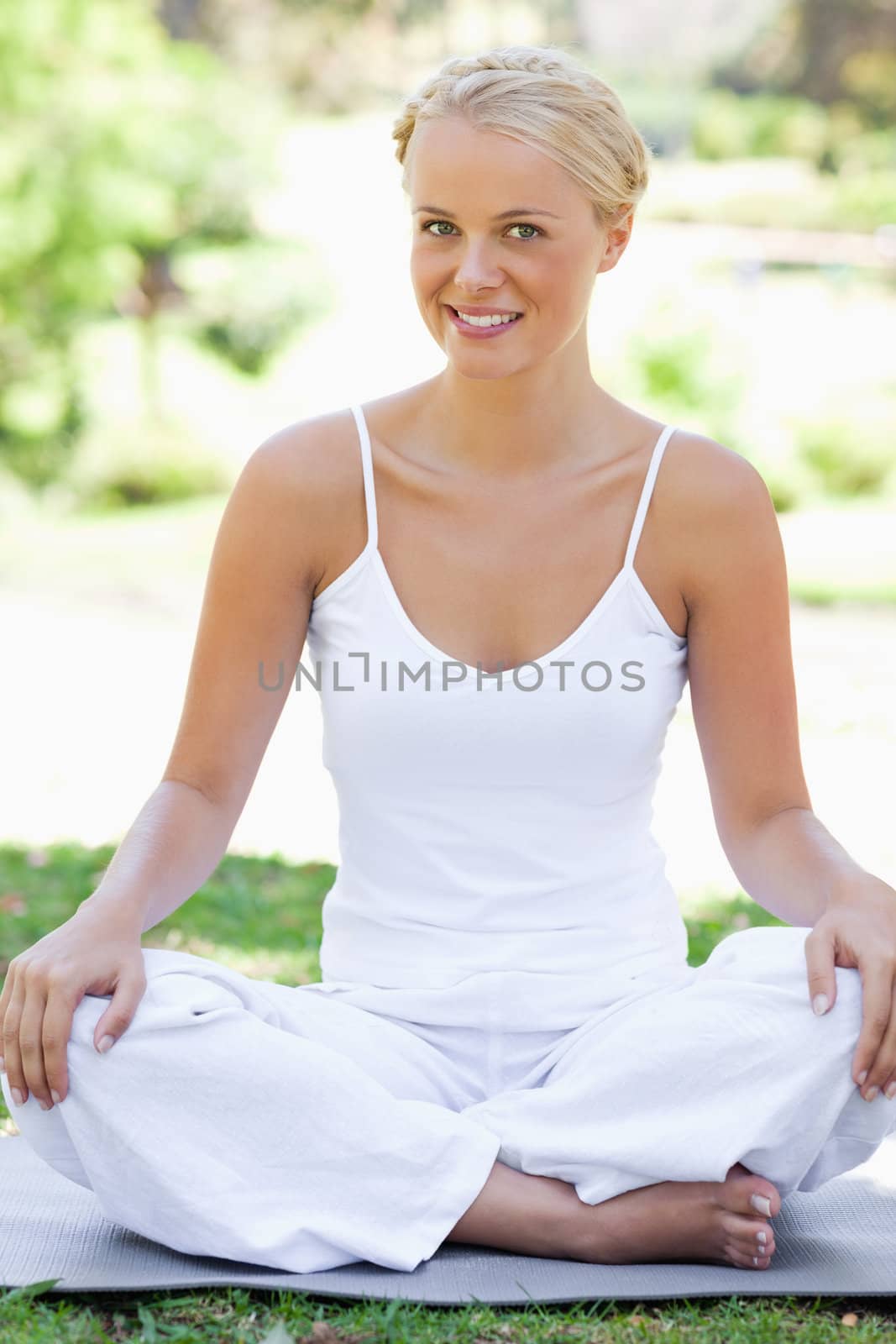 Smiling young woman in a yoga position on the grass