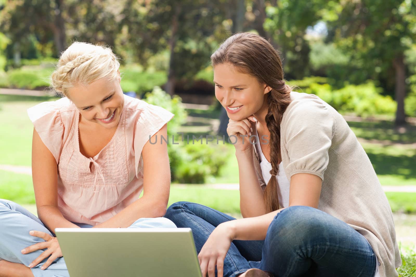 Smiling young women in the park with a laptop