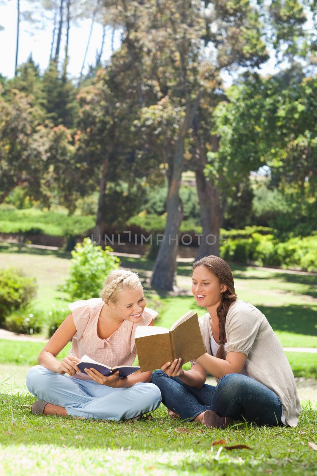Young woman showing her friend something in her book