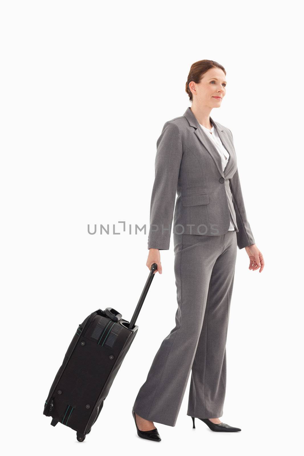 Smiling businesswoman with suitcase walking by Wavebreakmedia