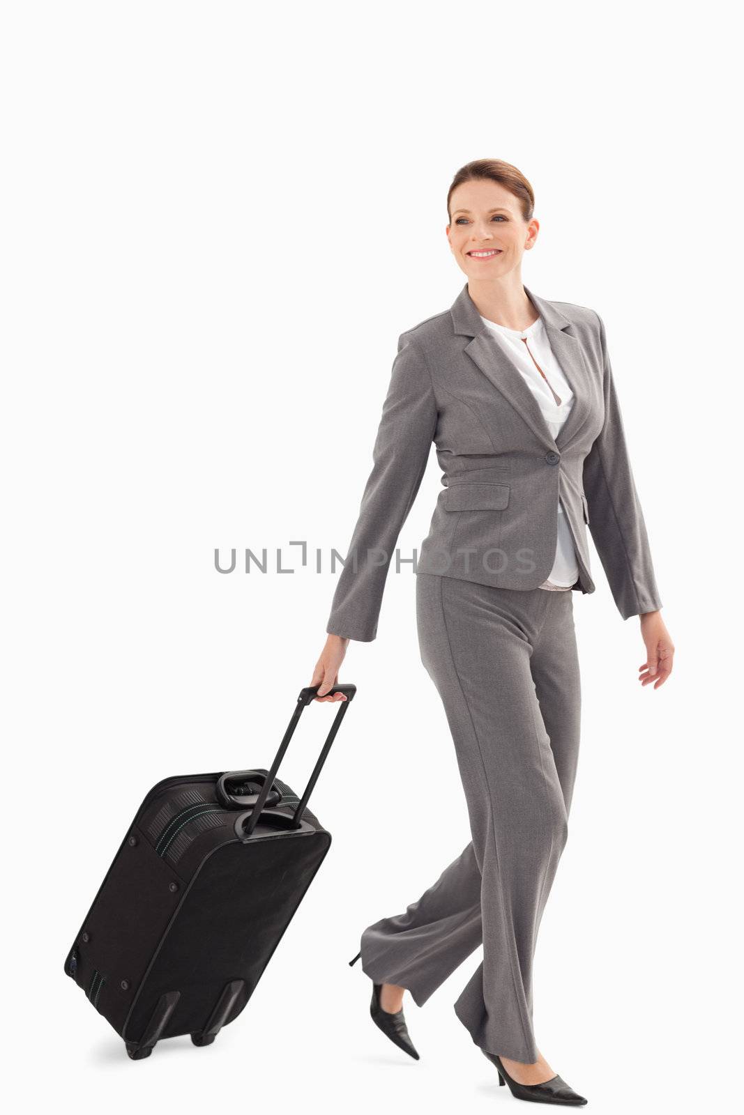 A businesswoman is smiling and walking with a suitcase
