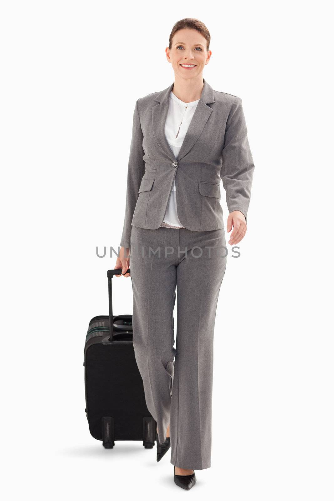 A businesswoman is walking forward with a suitcase