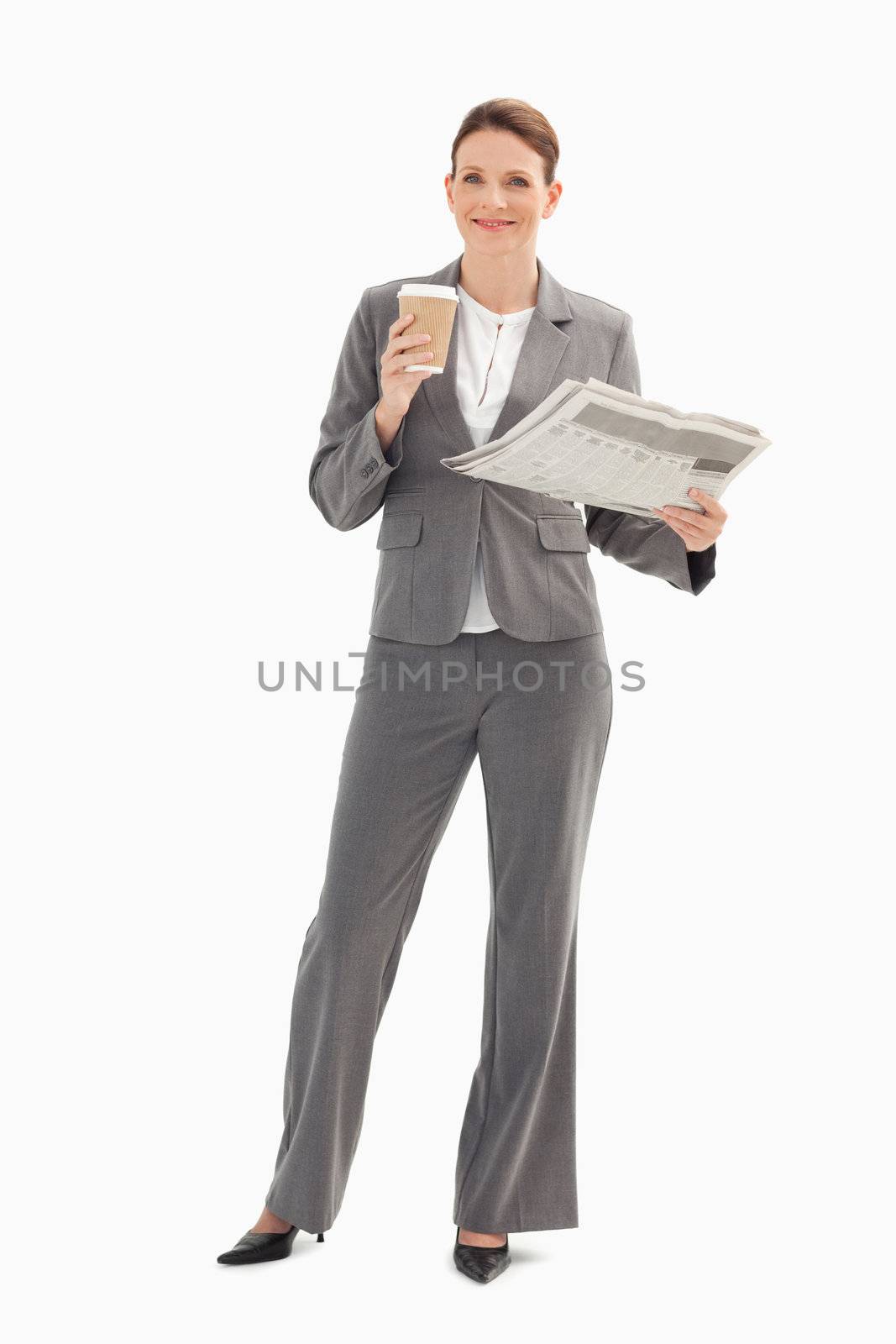 Smiling businesswoman holding cup and newspaper by Wavebreakmedia