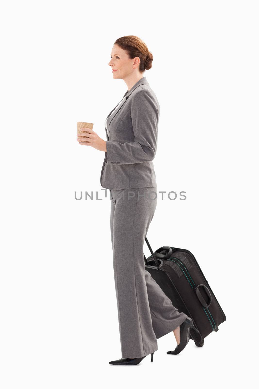 A businesswoman with a suitcase is holding coffee