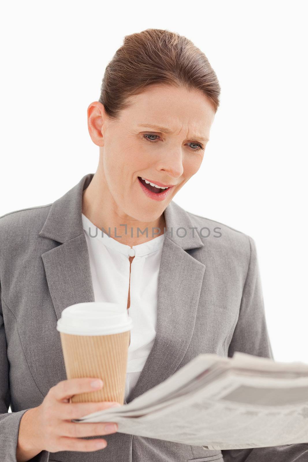 A surprised businesswoman is reading the newspaper