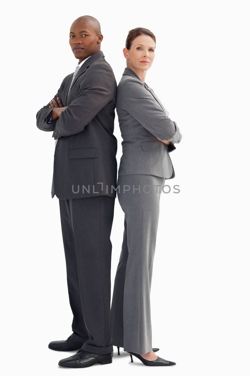 Business man and woman stand back to back by Wavebreakmedia