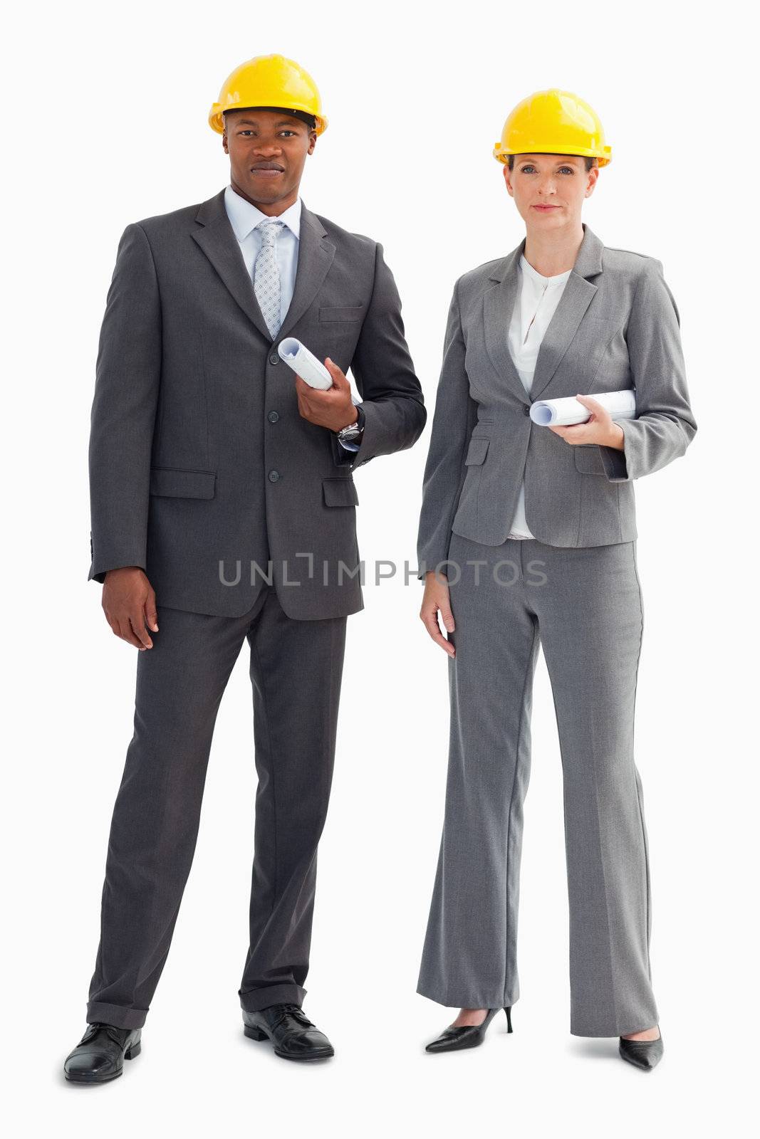 Two serious business people are wearing hard hats