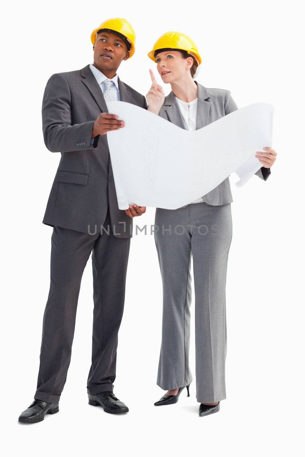 Two businesspeople wearing hard hats are discussing