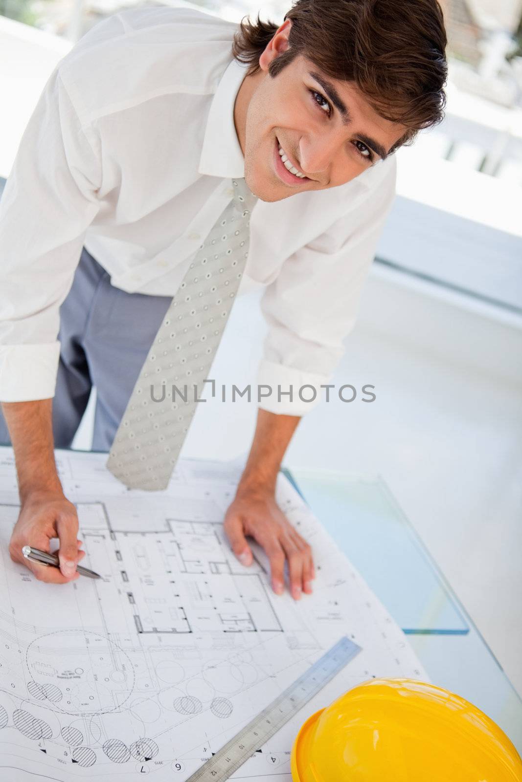 A smiling businessman works hard on his blueprints for work