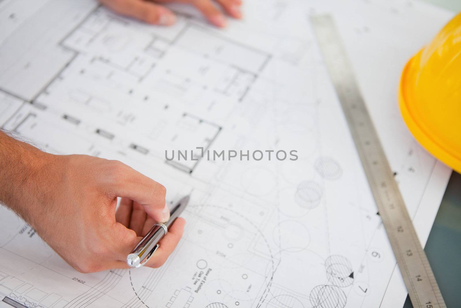 A close up shot of person with a pen making changes to the blueprints