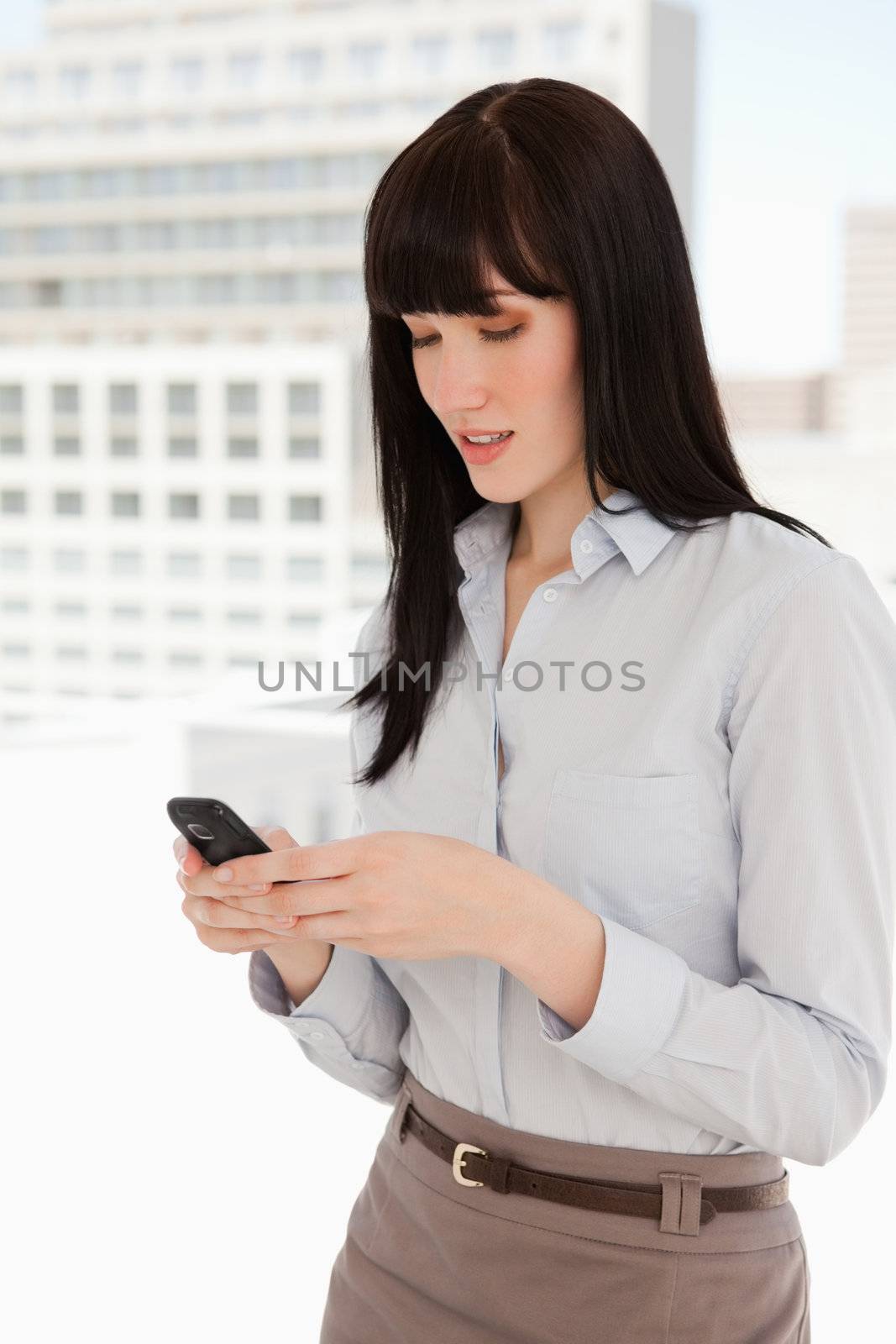 A woman using her phone to send a text message at work