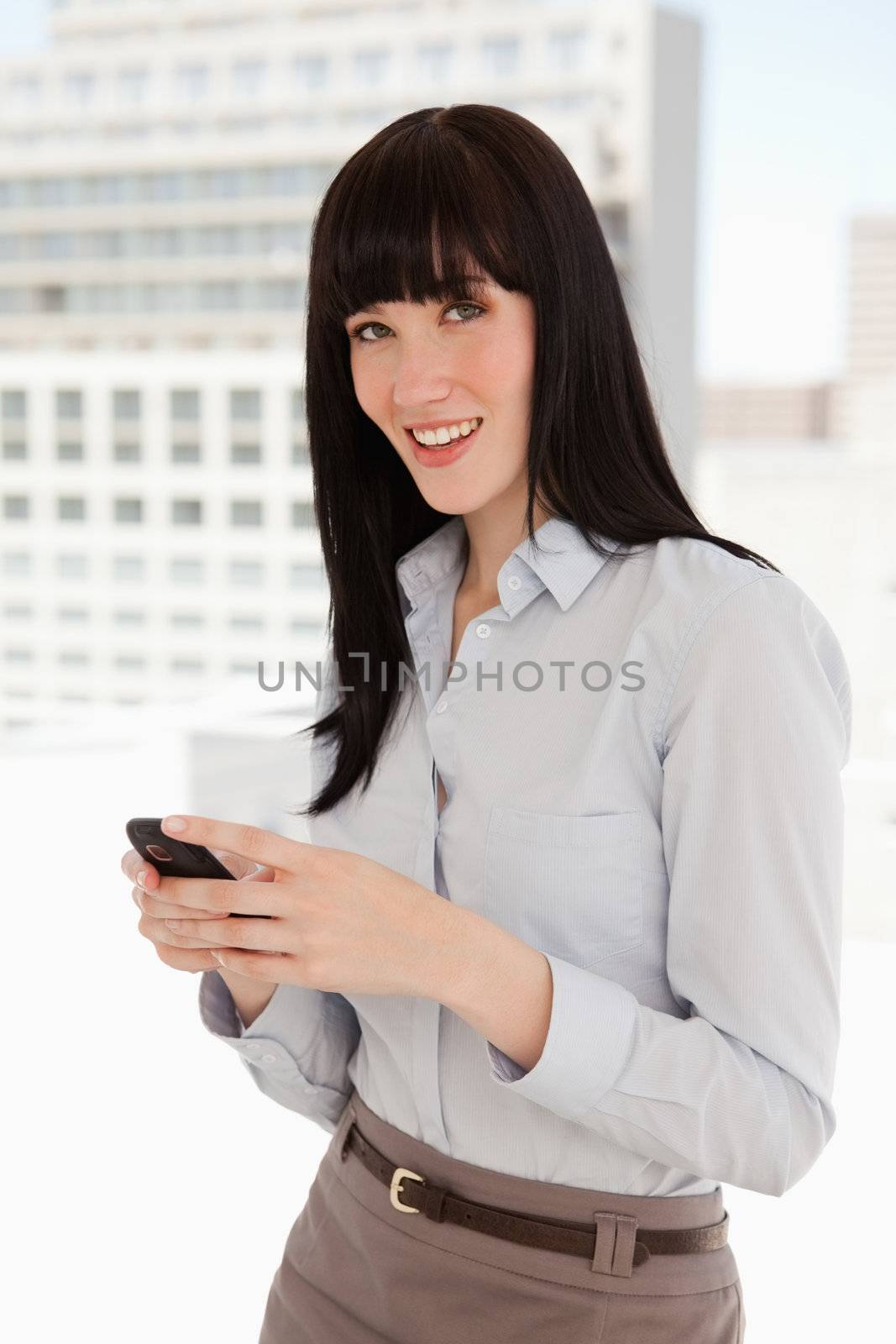A smiling woman texting on her mobile as she looks straight ahead
