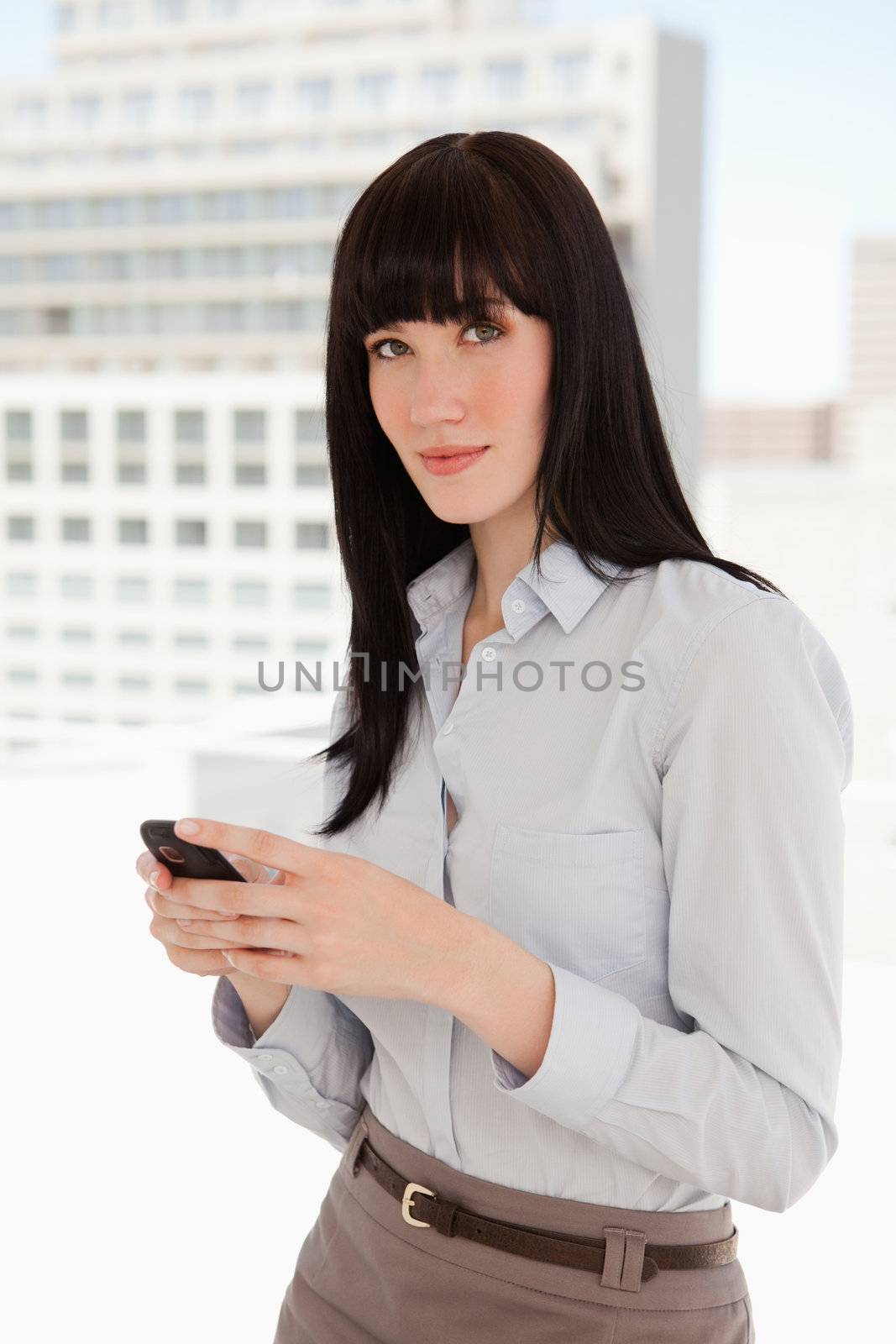 A business woman looks in front of her as she sends a text from her mobile phone