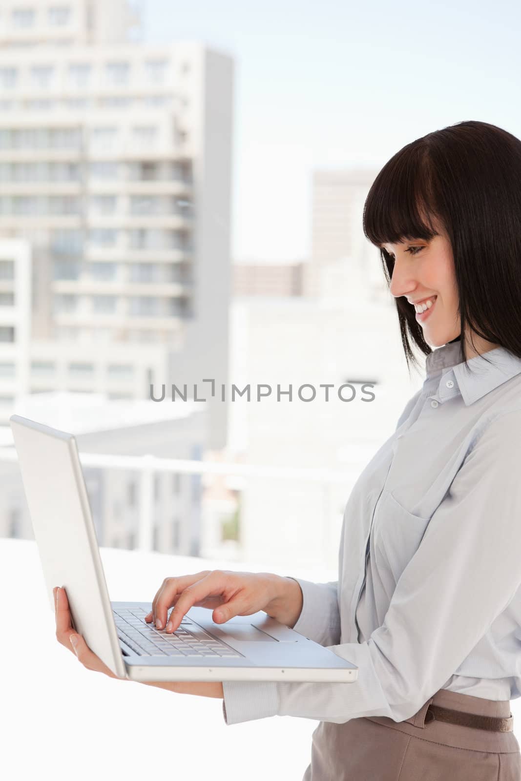A woman smiling in work as she uses her laptop