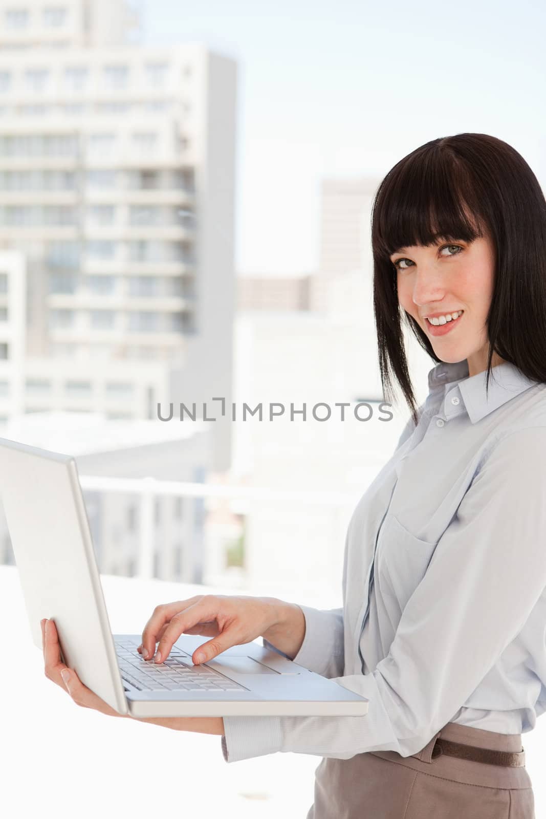 A smiling business woman looking at the camera as she uses her laptop