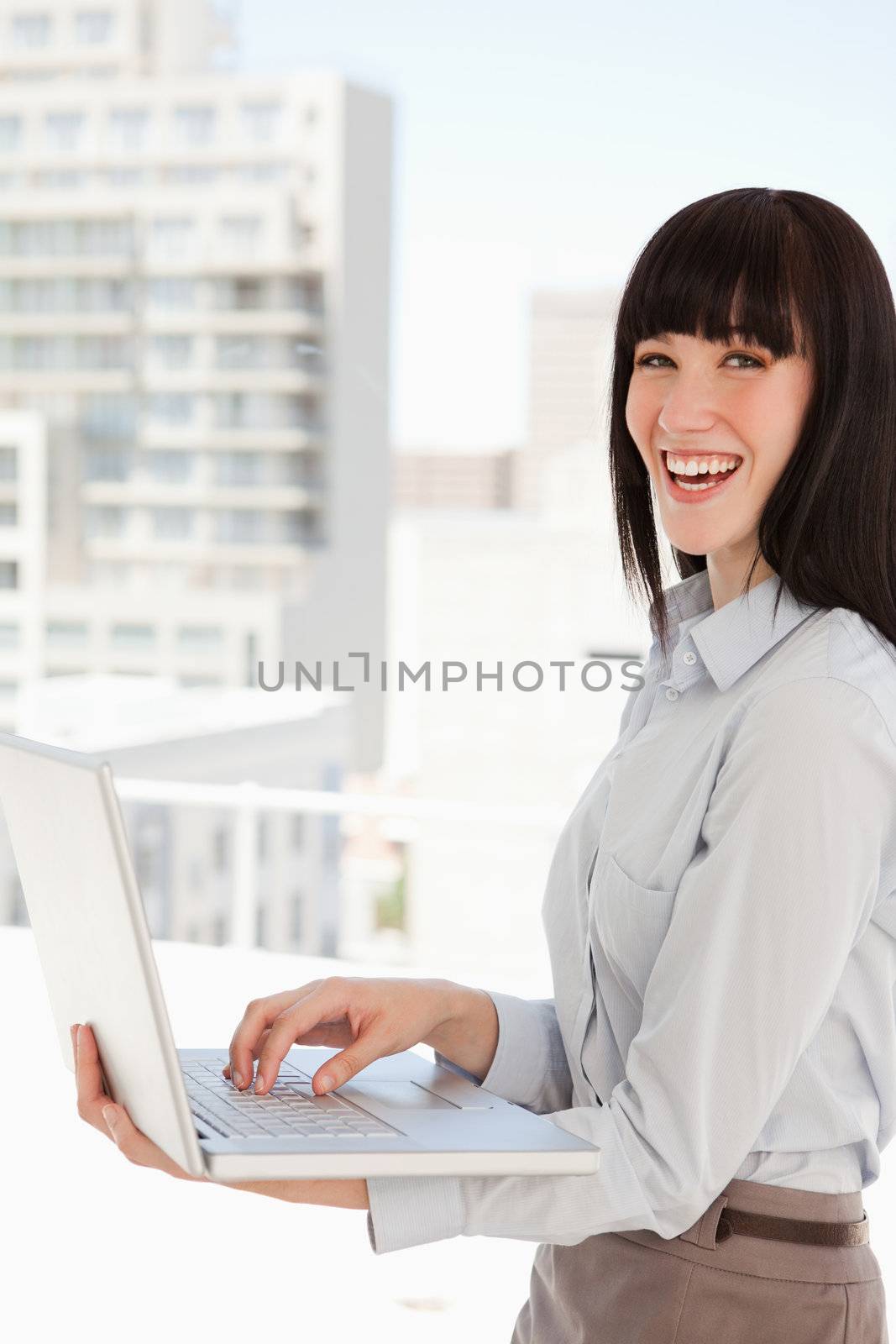 A laughing business woman with a laptop in her hands by Wavebreakmedia