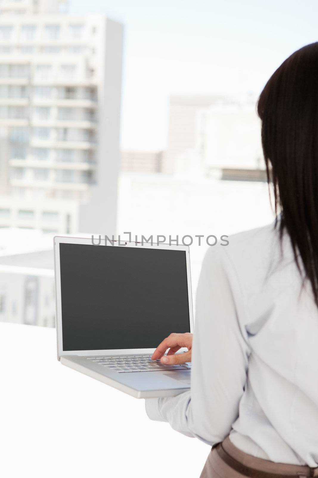 A business woman about to turn her laptop on with her back to the camera