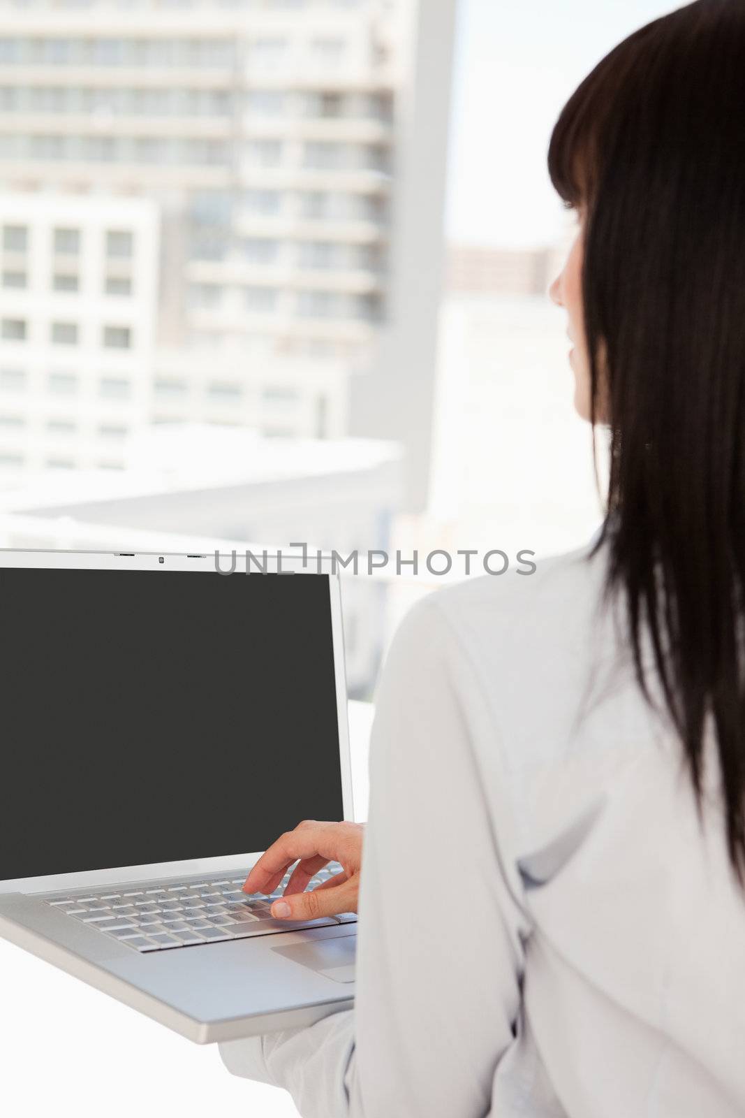 A business woman at work using her laptop while she looks out the window
