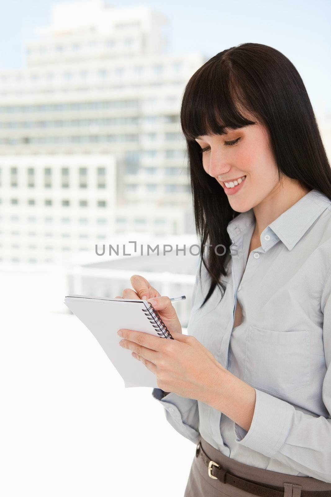 A woman in her office writing down notes on her note pad