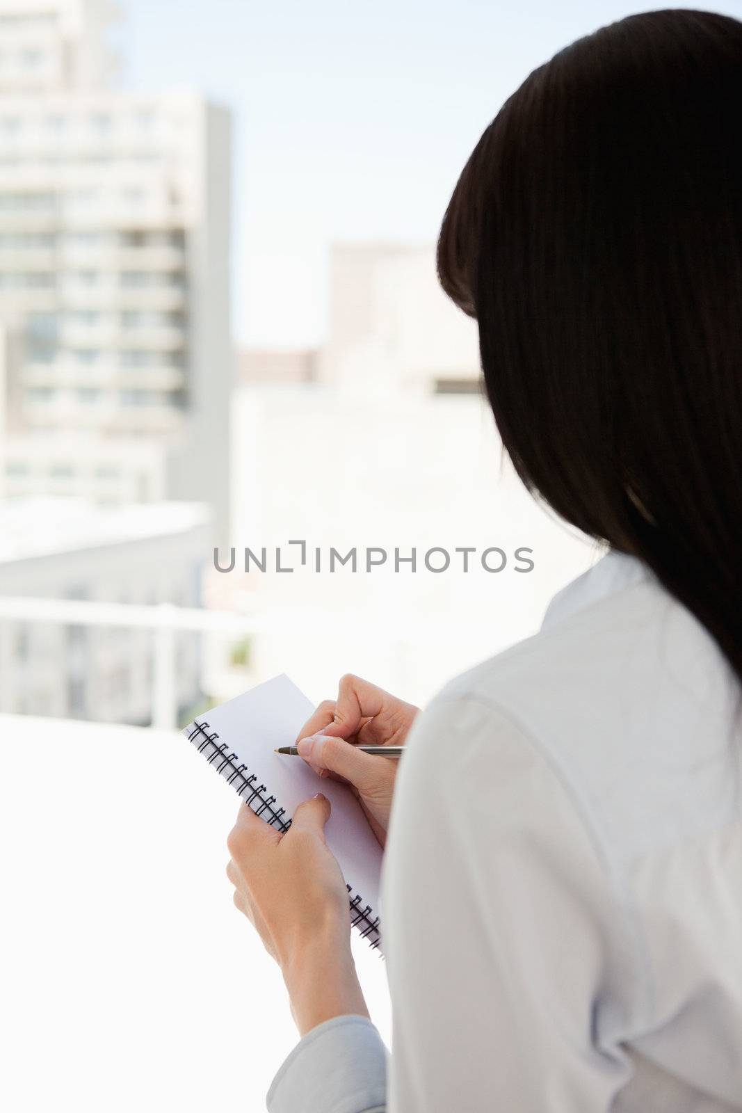 A woman with her back to the camera starts writing on her notepad