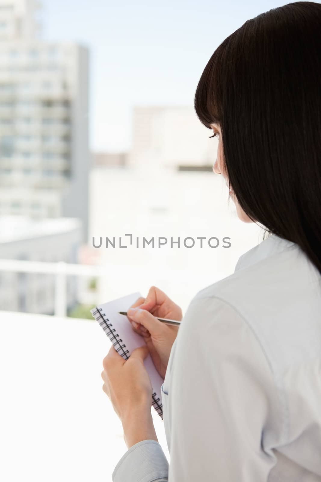 A woman with her back turned begins to write down some informati by Wavebreakmedia
