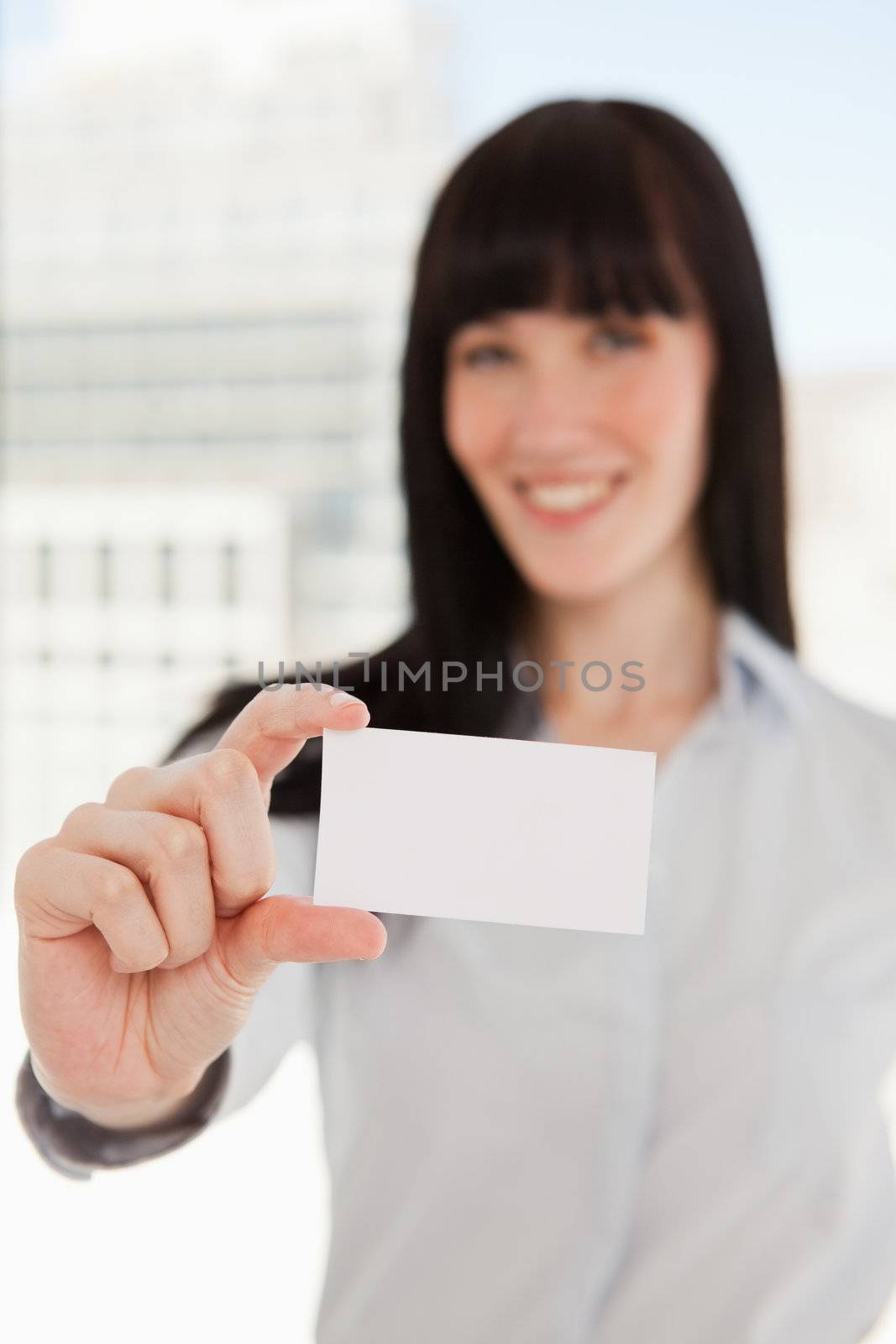 A focused shot on the business card as it is held by a business woman