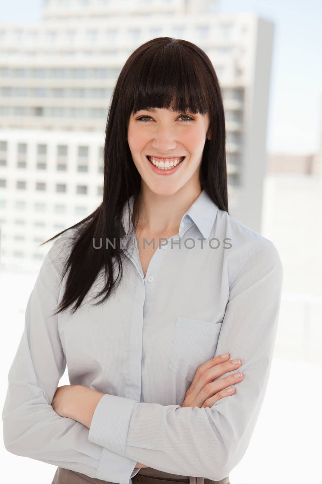 A woman smiling in her office and her arms folded
