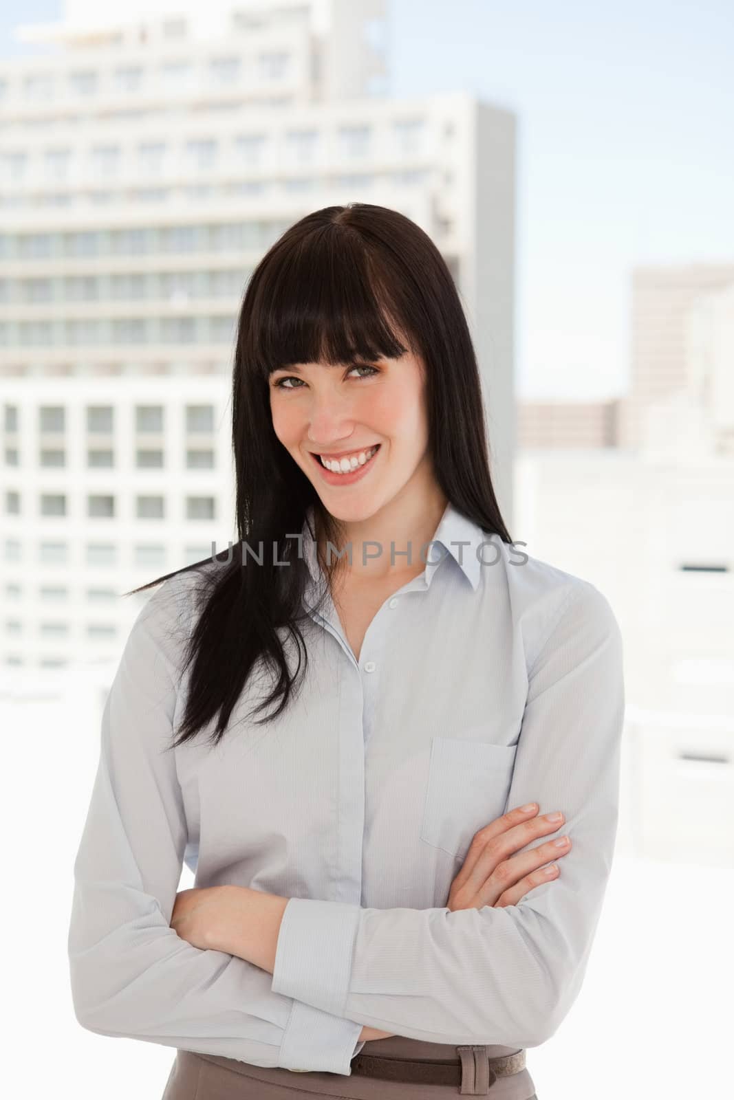 A business woman in her office smiling as she crosses her arms over