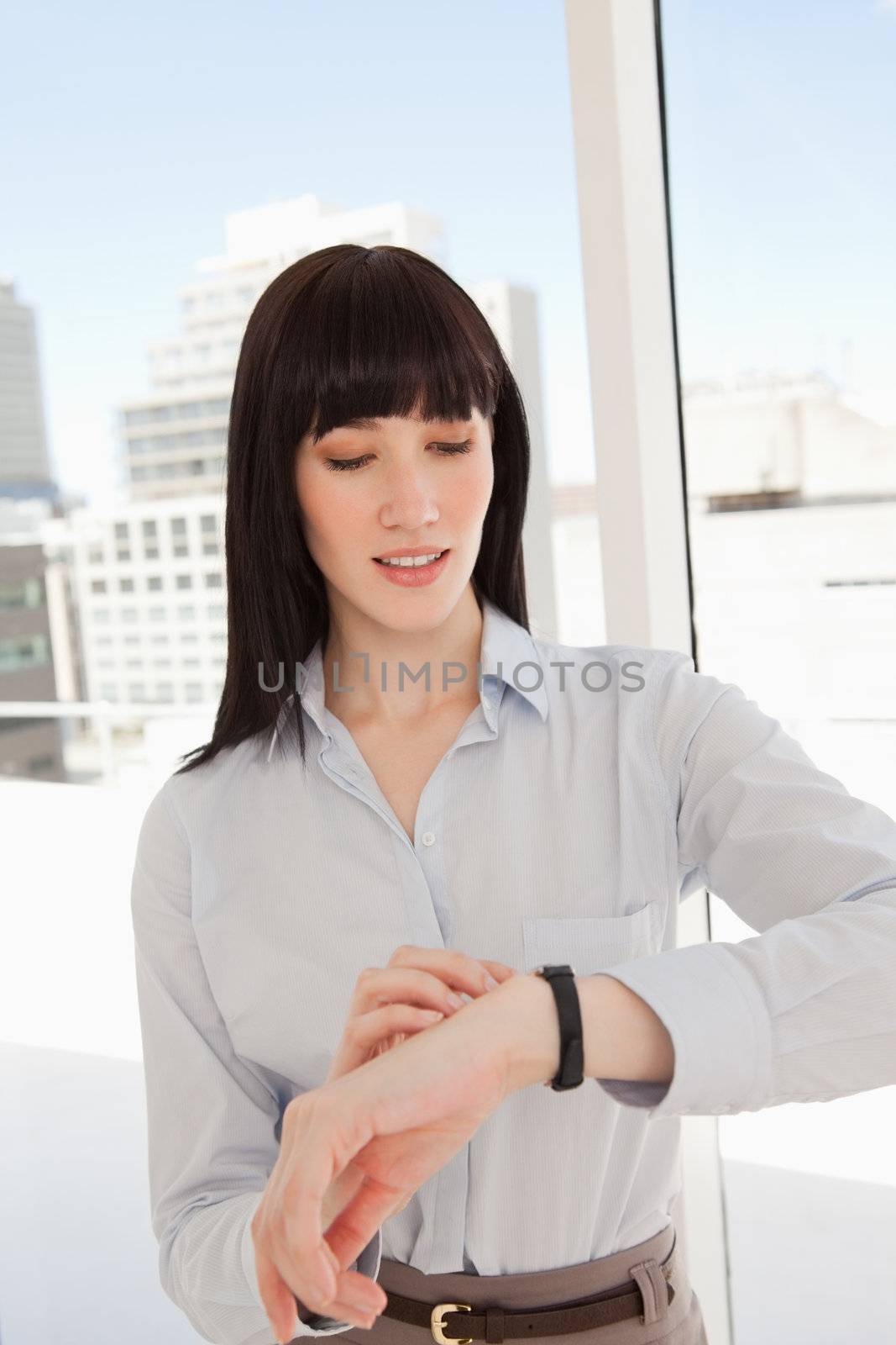 A business woman looking at her watch while in her office