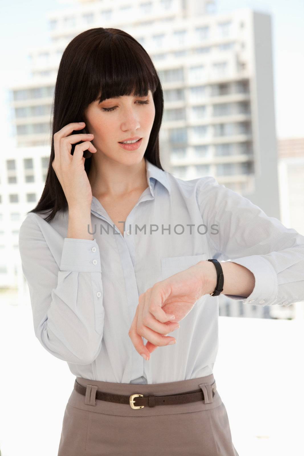A woman checking the time as she makes a phone call