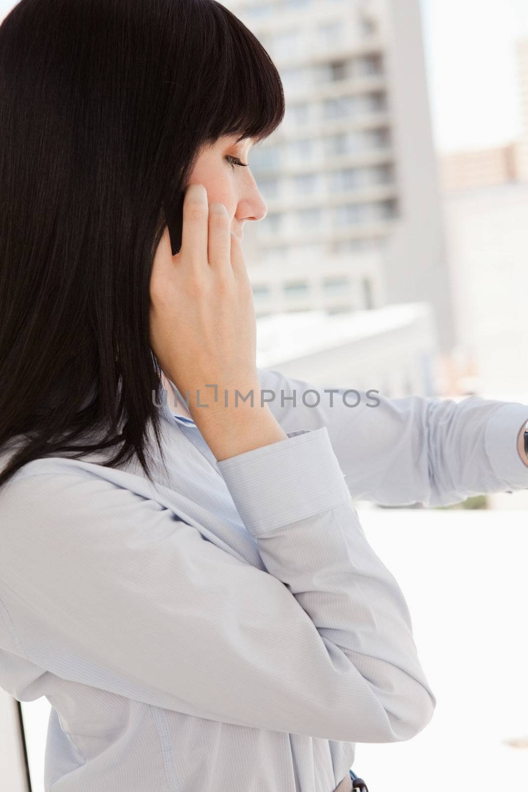 A woman making a call while she looks at her watch