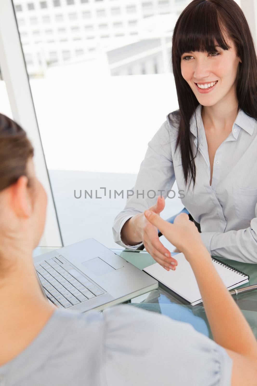 Both women move their hands closer to shake hands by Wavebreakmedia