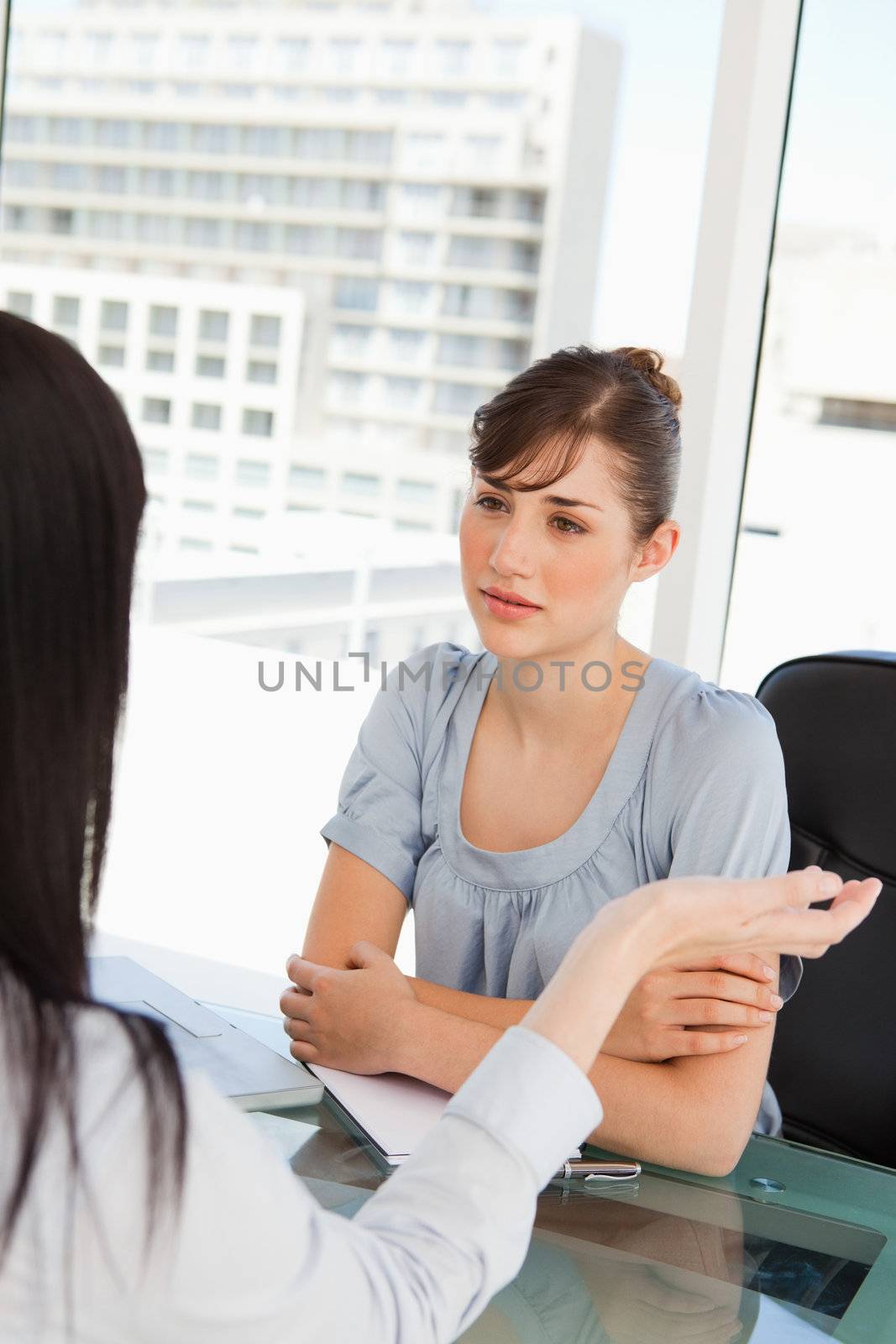 A brunette worker listens to her co-worker  by Wavebreakmedia