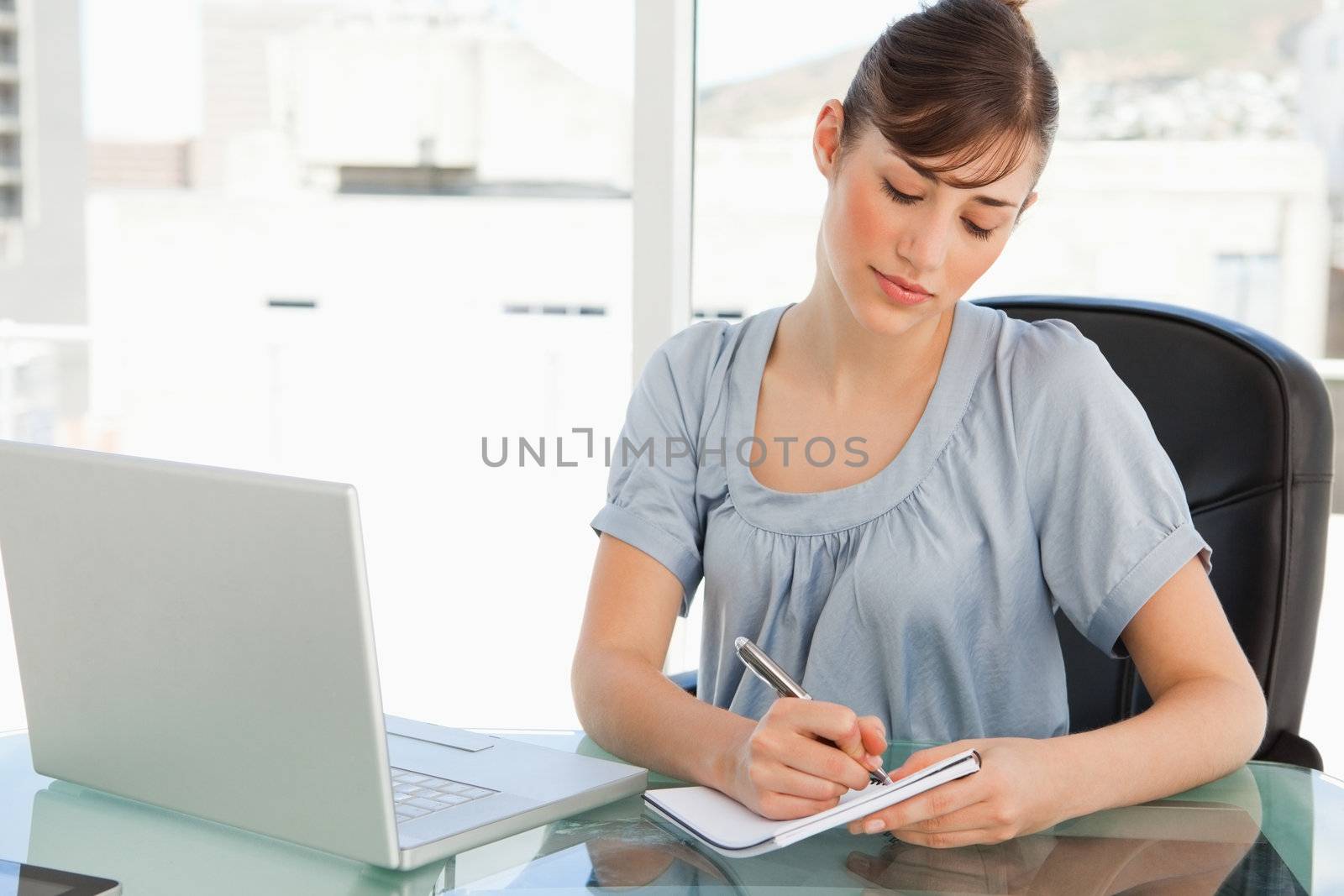 A woman takes down notes on her notepad by Wavebreakmedia