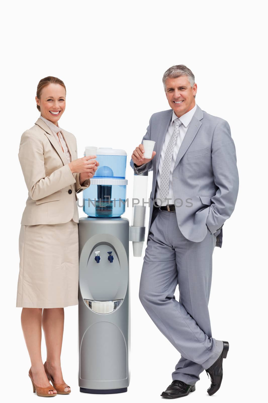 Portrait of business people smiling next to the water dispenser against white background