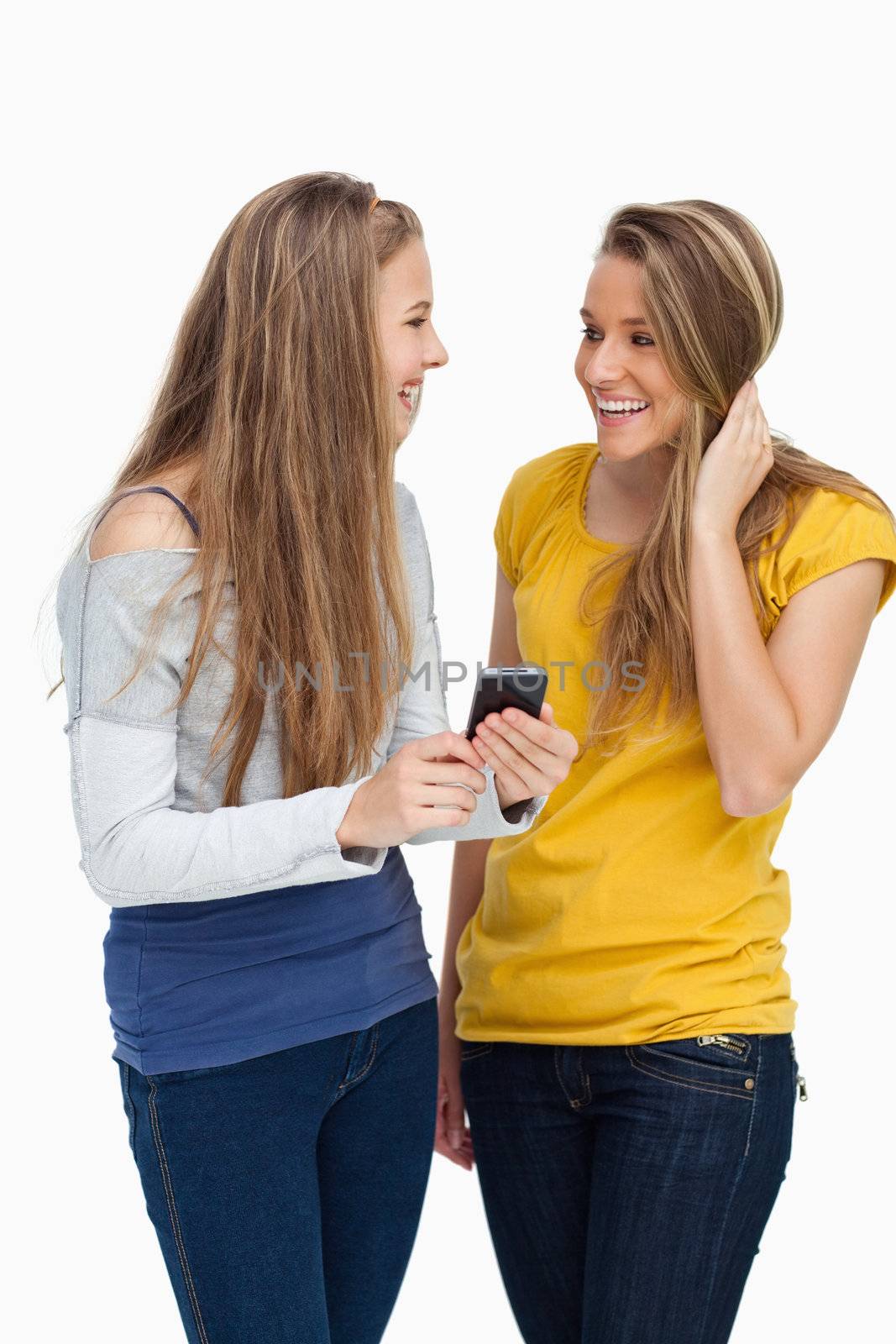 Two females student laughing while holding a cellphone against white background