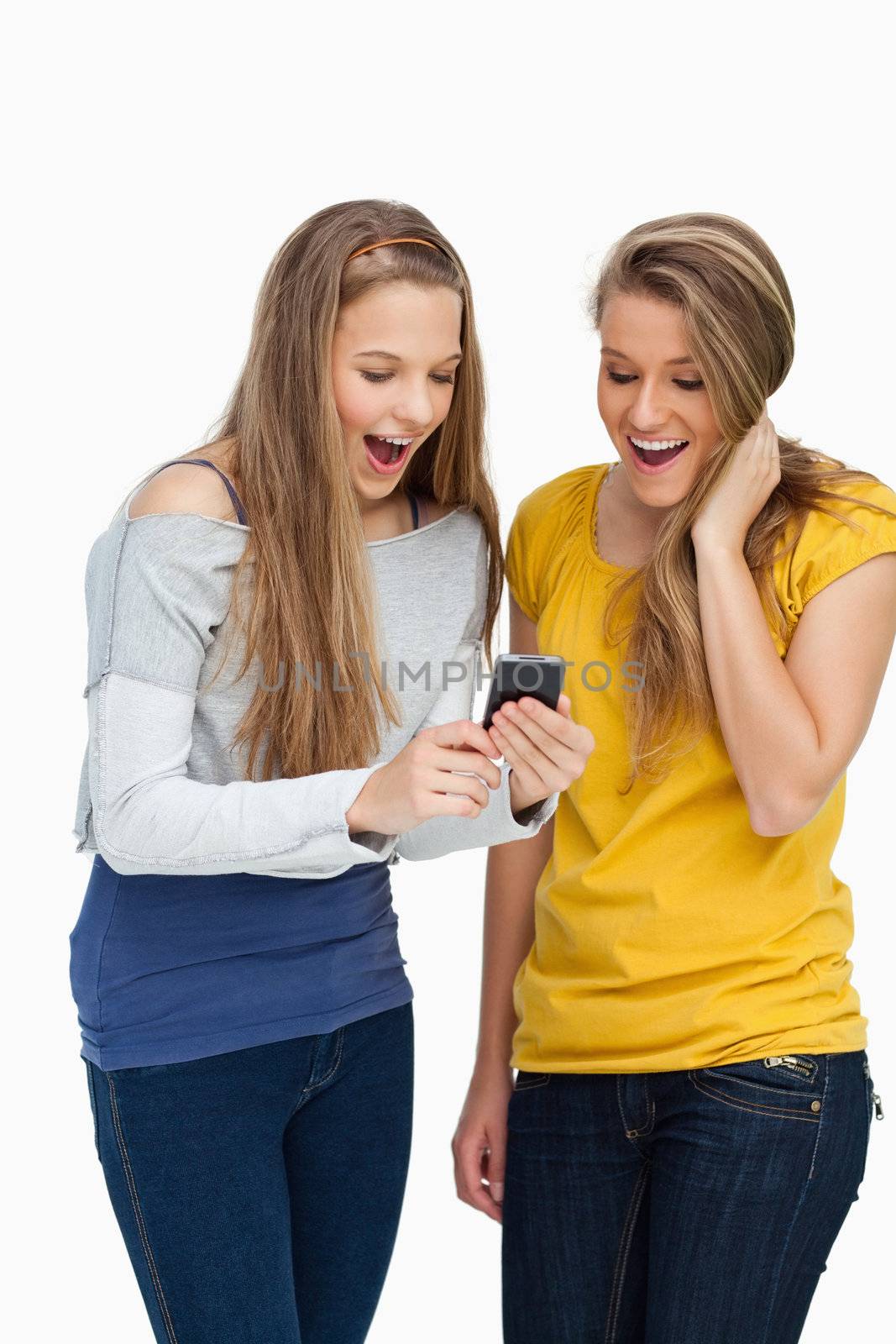 Two surprised students looking a cellphone screen against white background